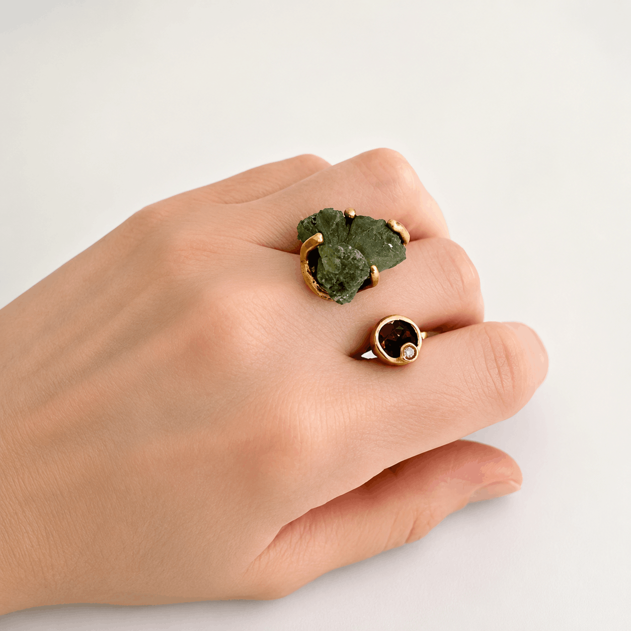 Bague contemporaine ouverte en bronze avec d'un côté une tourmaline verte brute et de l'autre côté une petite tourmaline rose.