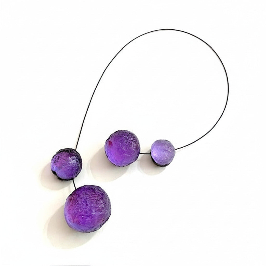 Collier graphique en résine composé de quatre sphères violettes texturées avec fermoir aimanté intégré dans deux éléments. Fabrication artisanale française.