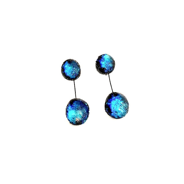Boucles pendantes composées de deux sphères en résine irisée bleue, reliées ensemble par un câble noir fin et solide. Pour oreilles percées.