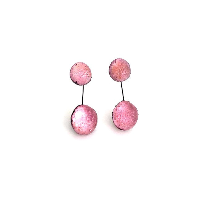 Boucles pendantes en résine rose pale, composées de deux sphère en résine texturée et irisée, reliées par un câble noir. Pour oreilles percées.