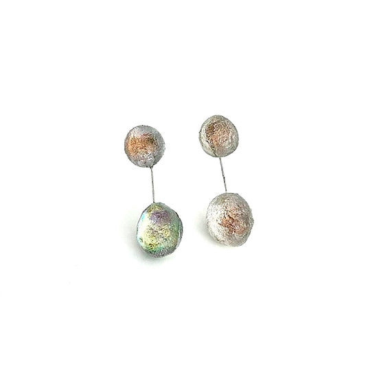 Deux sphères en résine irisée, reliées par un câble fin et solide, composent ces pendantes aux reflets changeants inspirés des teintes naturelles des opales blanches.