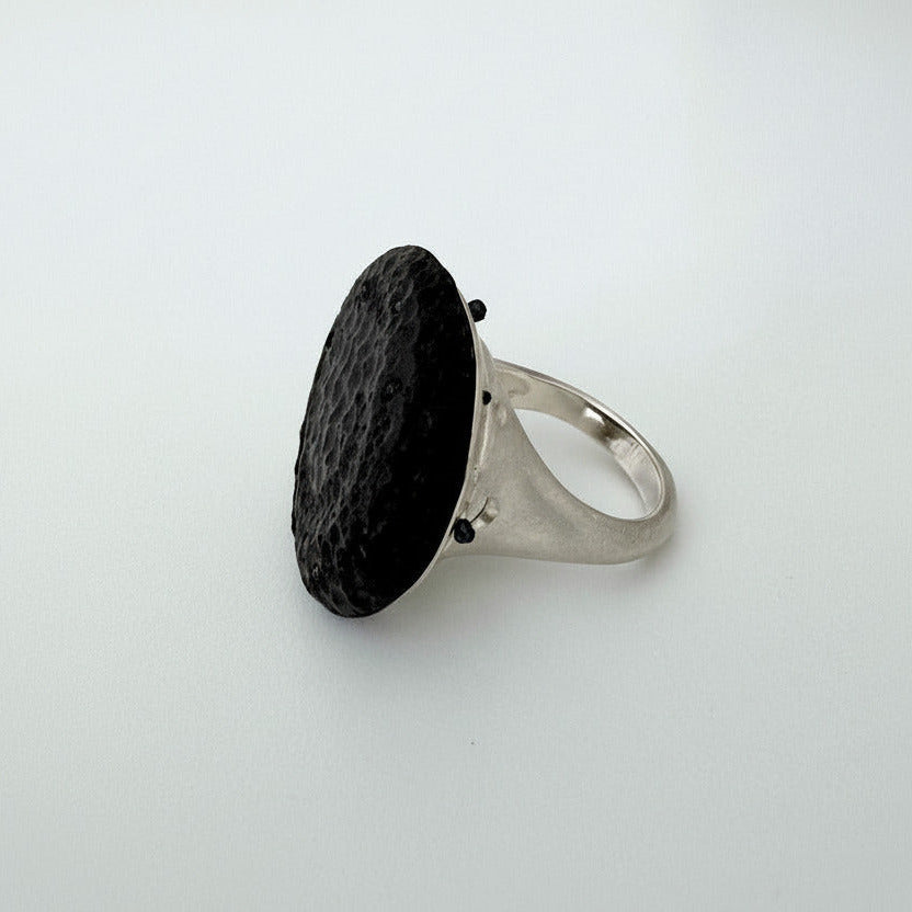Bague contemporaine présentant un cabochon en ébène sculpté souligné par 8 mini perles de verre noires. 