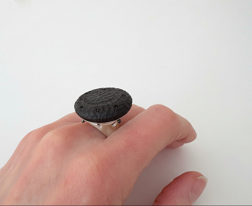 Bague contemporaine présentant un cabochon en ébène sculpté sur un corps de bague en argent satiné. Bijou porté