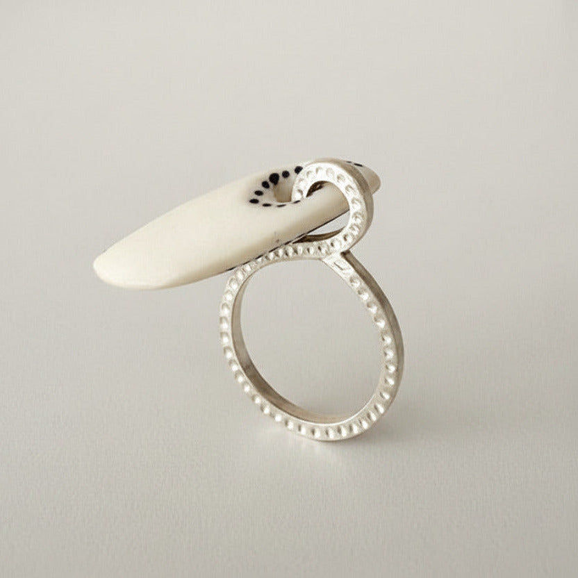 Bague design graphique os et anneau argent. Détail de l'anneau debout et de l'élément mobile en os sculpté sur le côté.