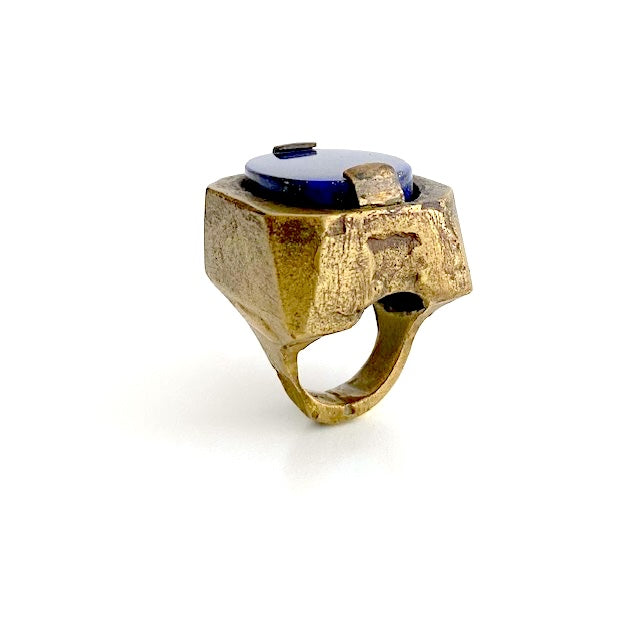 Bague sculpturale rectangulaire en bronze au centre un lapis-lazuli taillé ovale est serti par deux griffes. 