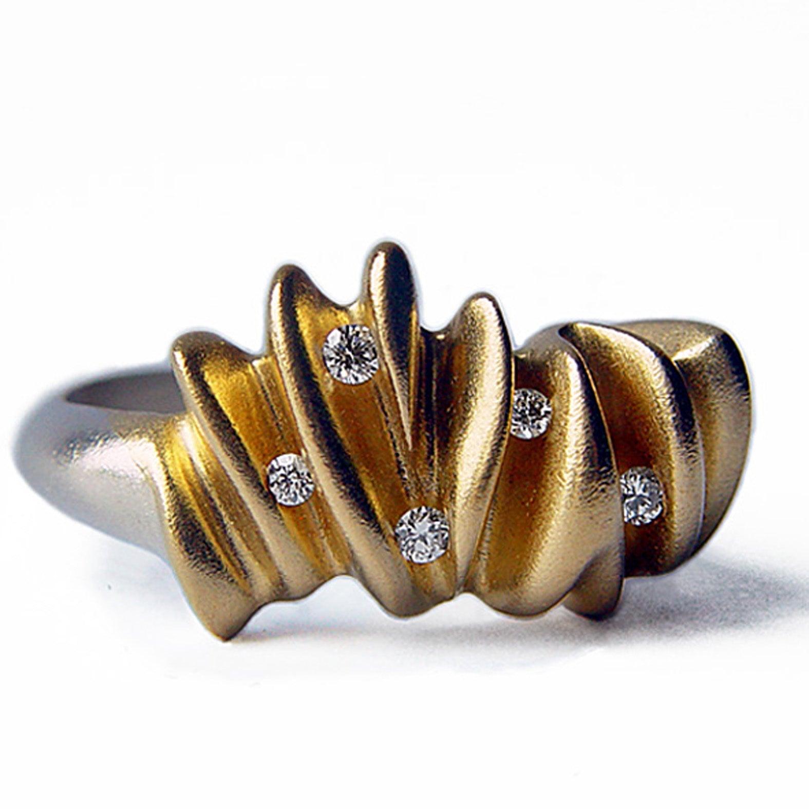 Une bague sculpturale inspirée par le mouvement des vagues. Façonnée en argent satiné, cette pièce présente des courbes fluides, sublimées par un plaquage en or et sertie de 5 diamants. 