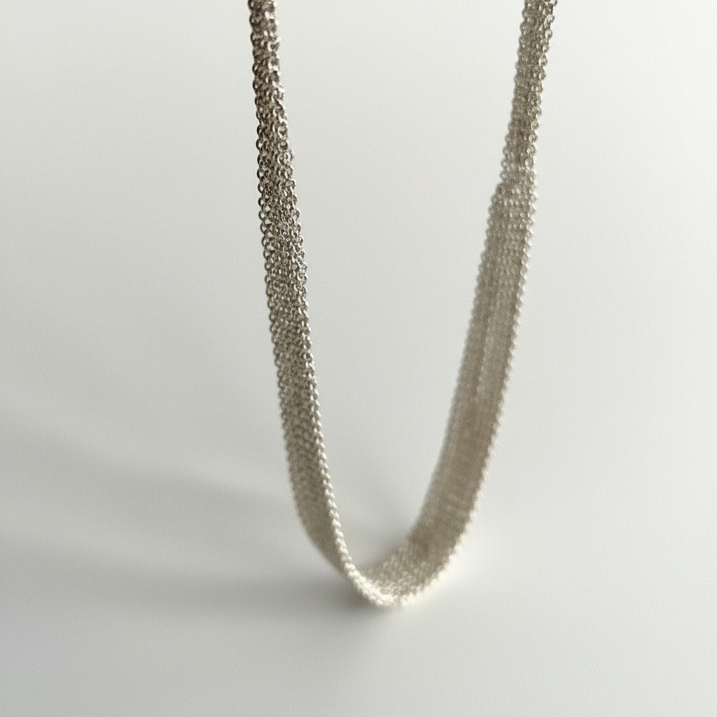 Tour de cou dégradé composé de plusieurs chaînes en argent assemblées  ensemble au fil de soie. Une création artisanal fait main par l'artiste belge Ria Lins