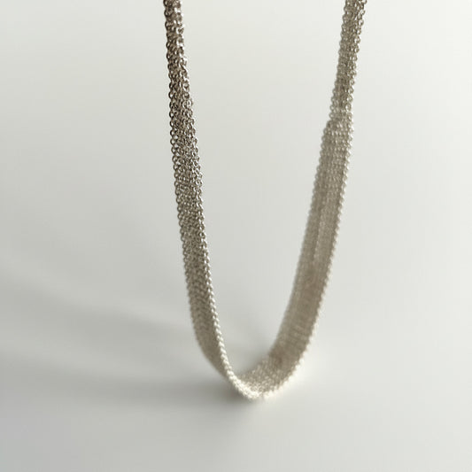 Tour de cou dégradé composé de plusieurs chaînes en argent assemblées  ensemble au fil de soie. Une création artisanal fait main par l'artiste belge Ria Lins