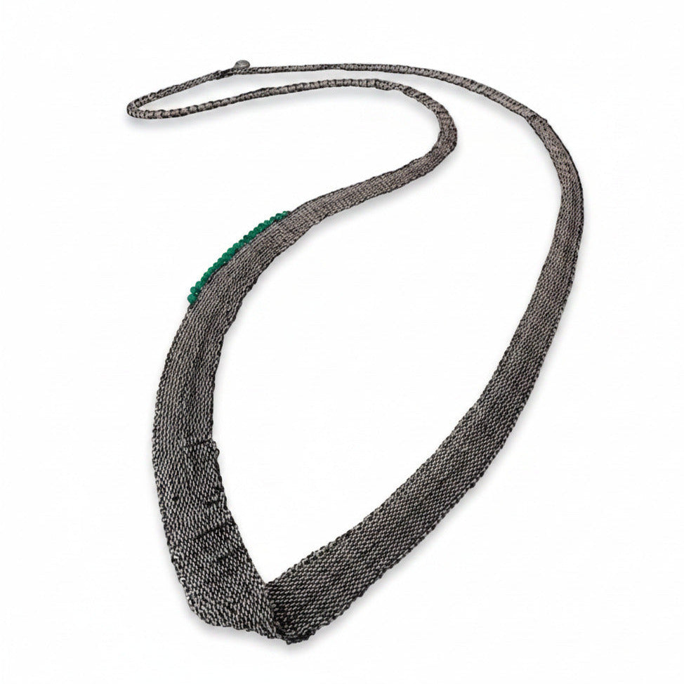 Sautoir composé de chaines en argent oxydé noir assemblées au fil de soie, orné de 20 mini perles d’agate verte cousue sur un côté du bijou. Pièce unique artisanale.