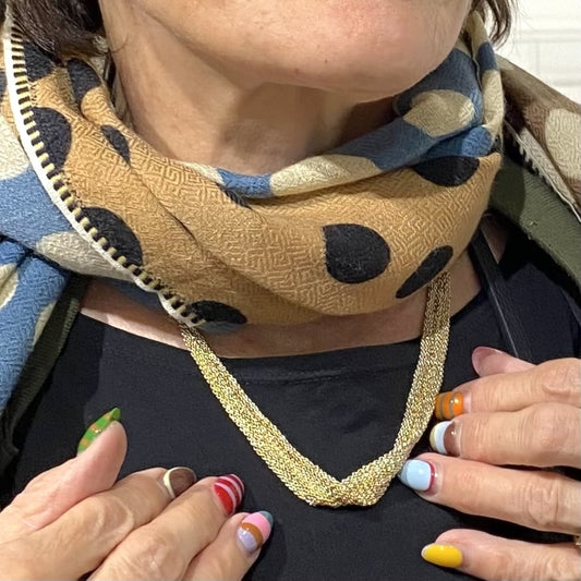 Tour de cou forme ruban, composé d'un assemblage de chaînes d'argent dorées au fil de soie. Bijou porté.