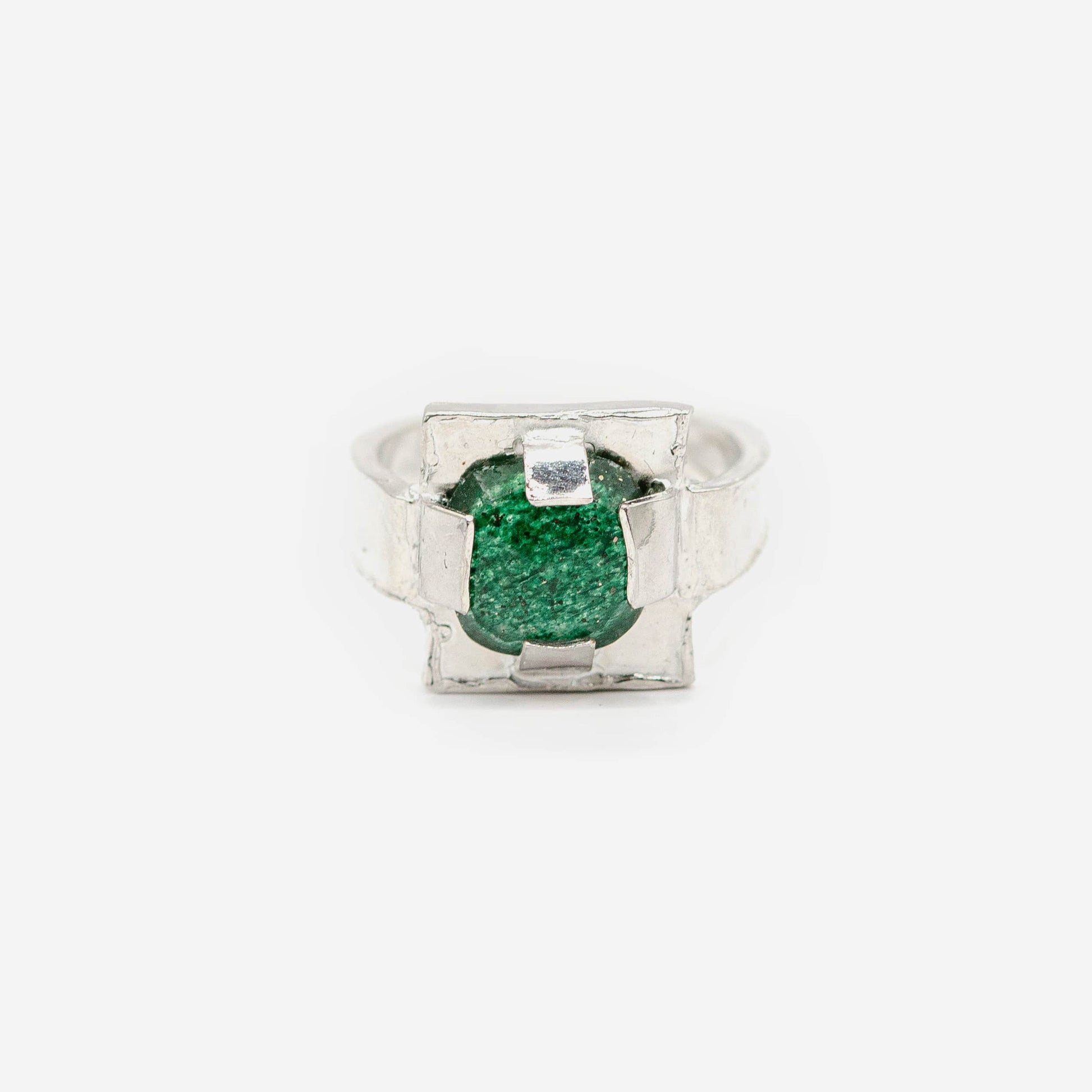 Bague carrée en argent et jade vert facetté. Plutôt que de simplement maintenir le jade, le sertissage devient ici une véritable structure sculpturale, dessinant un cadre irrégulier qui souligne la présence de la pierre.