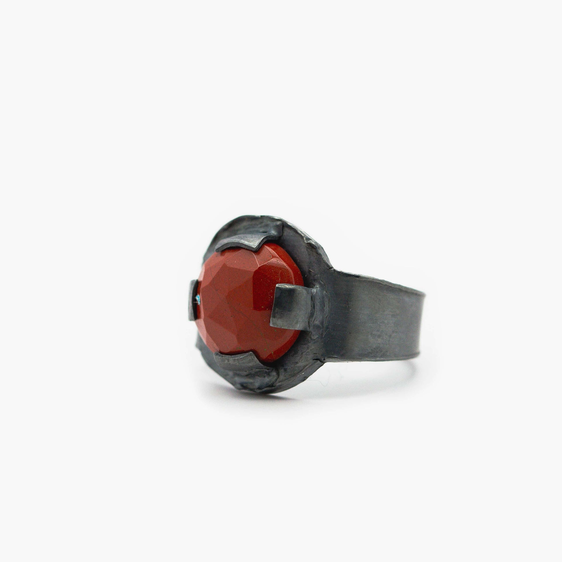 Bague architecturale en argent oxydé avec sertissage contemporain autour d'un jaspe rouge facetté.