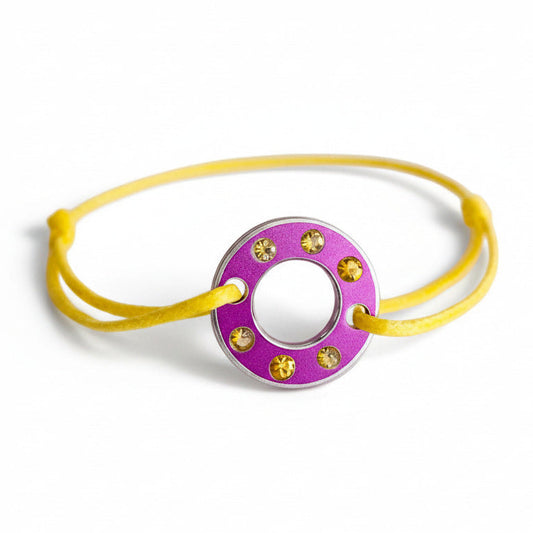 Bracelet Ready-Made composé d'une rondelle en aluminium violet sertie de  six saphirs jaunes facettés. Bracelet design et unisexe présenté sur lien de coton ciré. 