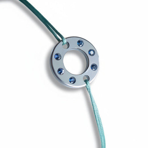 Bracelet Ready-Made, rondelle en  aluminium argenté et six saphirs bleus. bijou upcyclé inspiration moto, présenté sur lien de coton réglable. 