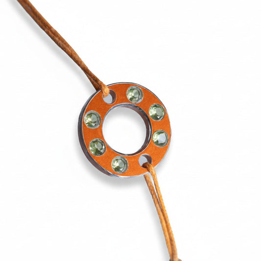 Bracelet Ready-Made en rondelle d'aluminium orange, sertie de  six péridots. Un bracelet cntemporain et unisexe présenté sur lien de coton ciré orange. 