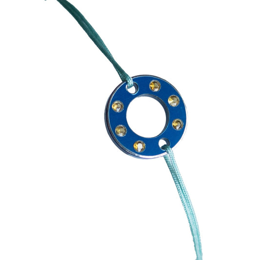 Bracelet Ready-Made en rondelle d'aluminium bleu et six saphirs blancs, présenté sur lien de coton ciré bleu ajustable. bracelet contemporain upcyclé et unisexe.