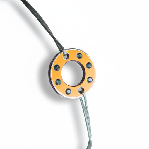 Bracelet Ready-Made petit modele composé d'une rondelle en aluminium orange, sertie de  six tourmalines vertes. Un bracelet contemporain et unisexe présenté sur lien de coton ciré.