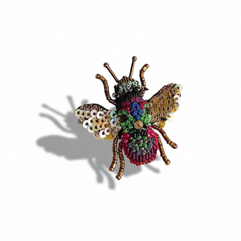 Broche Abeille Arc en ciel brodée à la l'aiguille avec de mini perles de verre et des sequins dans des couleurs irisées de doré, fuchsia et vert. Une création artisanale signée Trovelore.