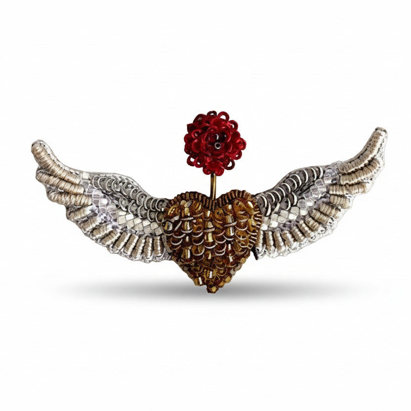 Broche en textile brodé et petites perles de verre. Représente un cœur doré en deux ailes déployées argenté, inspirée par les oiseaux et les anges. Une fleur rouge brodée sur le dessus symbolise le renouveau.