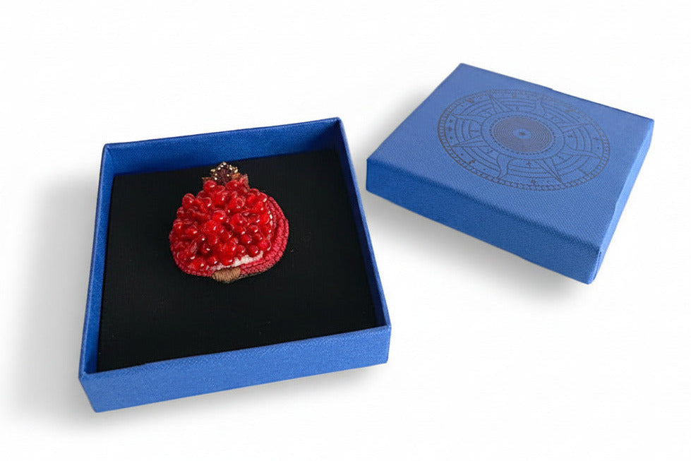 Prête à offrir, La broche broche est présentée dans une boîte bleue signée Trovelore, accompagnée de sa notice explicative détaillant le travail de broderie et le savoir-faire artisanale.