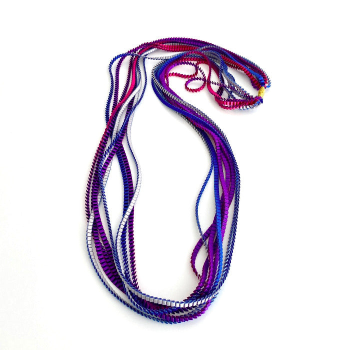 Long sautoir coloré composé de huit bandes de satin plissé violet, silver, fushia et bleu royal reliées les unes aux autres par un lien de coton jaune