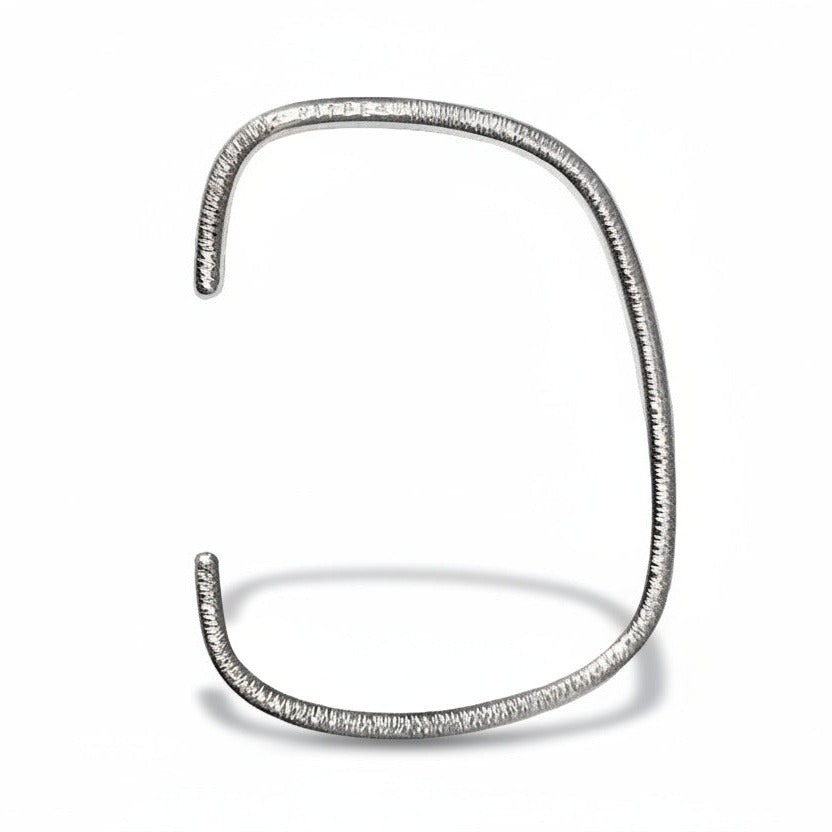 Bracelet géométrique ouvert forme jonc en argent martelé finition intérieur poli. Bracelet artisanal contemporain signé Anne Milbeau.