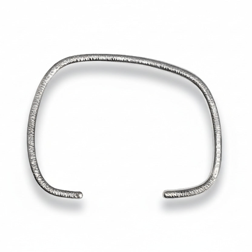 Bracelet géométrique en argent forgé au fil rond, jonc ouvert au design asymétrique. Modèle mixte, surfaces striées  et intérieur poli. Bijou design contemporain, bijou minimaliste, une création artisanale signée Anne Milbeau.
