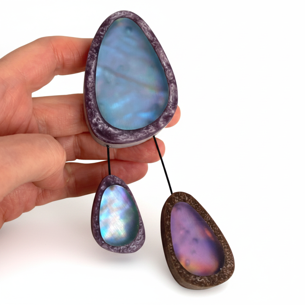 Grande broche contemporaine en résine bleu et violet composée de trois éléments de différentes tailles,deux petits éléments sont reliés au plus grand par un cable rigide noir. fermeture aimant. Fabrication française.