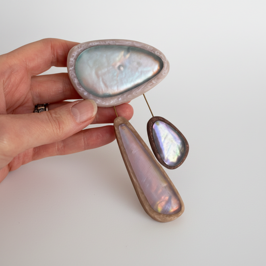 Broche XL composée de 3 éléments de différentes tailles en résine couleurs pastel bleu clair,rose,bleu. les deux petits éléments sont reliés au grand par un cable rigide noir. fermeture aimant.broche tenue par main de femme